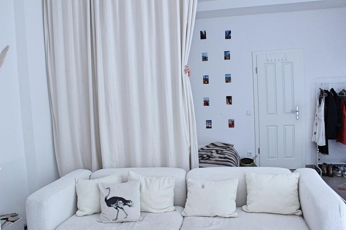 Raumteiler Vorhang trennt Wohnbereich und Schlafzimmer in einem offenen Raum.