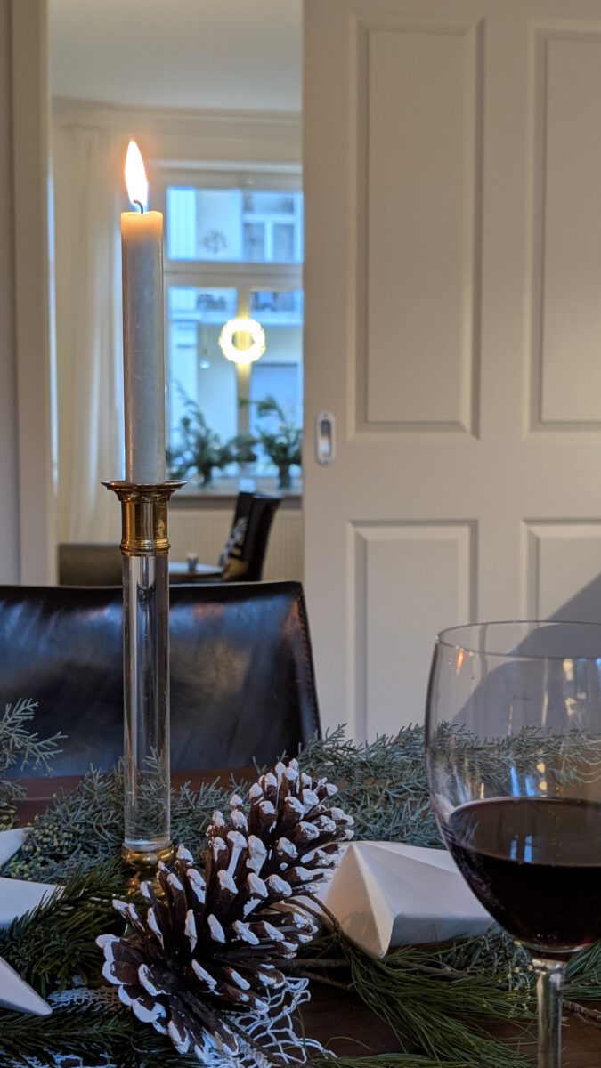 Tannengrün auf dem Tisch und ein leuchtender Kranz im Fenster sorgen für festliche Weihnachtsstimmung.