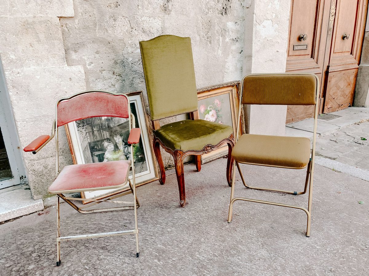 Drei unterschiedliche Vintage Stühle stehen vor einer Hauswand auf der Straße